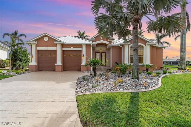 view of front of property with a garage and a yard