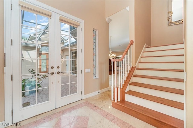 entryway with a chandelier, light tile patterned floors, and french doors