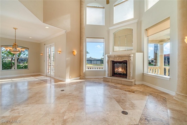 unfurnished living room with a high end fireplace, a high ceiling, a wealth of natural light, and ornamental molding