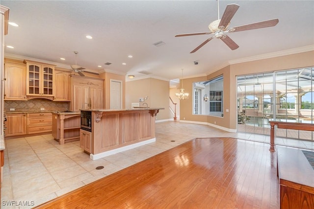 kitchen with a kitchen island, ornamental molding, light brown cabinetry, and tasteful backsplash