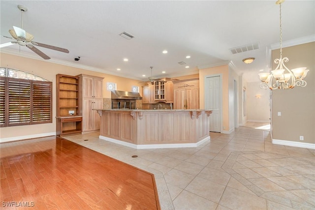 kitchen featuring a large island, crown molding, a breakfast bar, and range hood