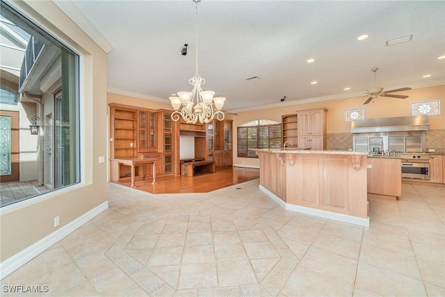 kitchen featuring a kitchen breakfast bar, backsplash, oven, a kitchen island with sink, and ornamental molding