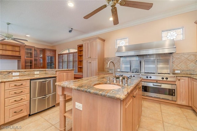 kitchen with light stone countertops, sink, decorative backsplash, light brown cabinetry, and a center island with sink