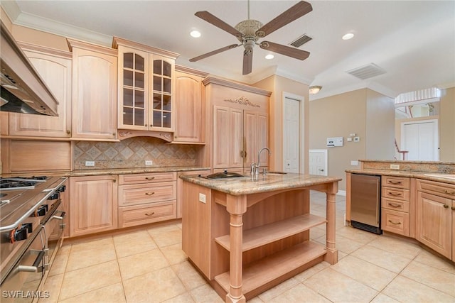 kitchen with backsplash, a kitchen island with sink, and light brown cabinetry