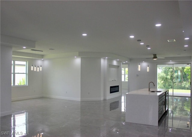 kitchen with an island with sink, ceiling fan, and sink