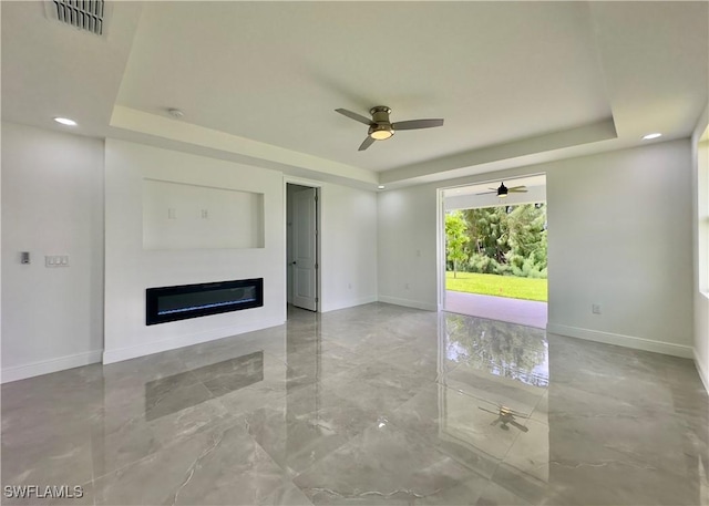 unfurnished living room featuring a raised ceiling and ceiling fan