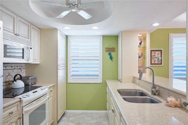 kitchen featuring light stone counters, sink, ceiling fan, and white appliances