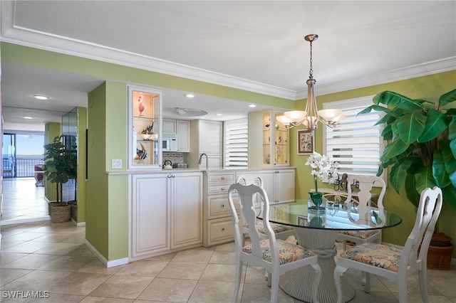 tiled dining area with plenty of natural light, ornamental molding, and an inviting chandelier