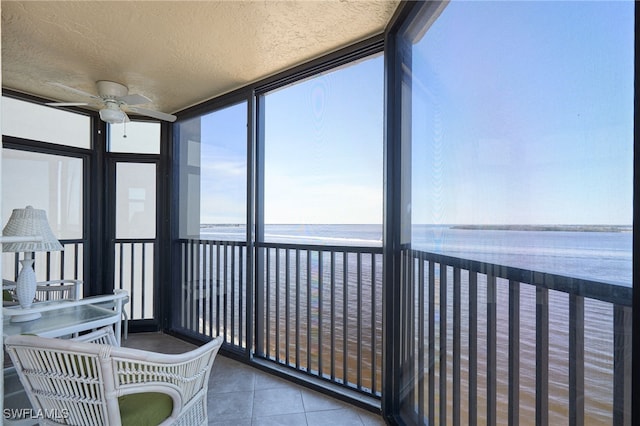 sunroom with a wealth of natural light, ceiling fan, and a water view