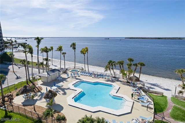 view of swimming pool featuring a water view, a patio, and a view of the beach