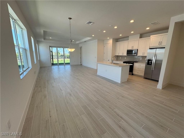 kitchen with stainless steel appliances, a sink, visible vents, open floor plan, and backsplash