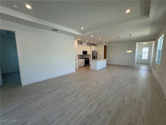 unfurnished living room with light wood finished floors, visible vents, baseboards, and recessed lighting