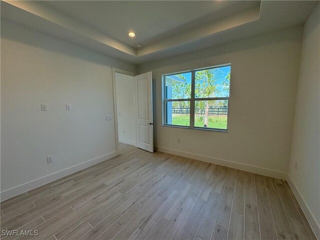 unfurnished room with baseboards, a tray ceiling, wood finished floors, and recessed lighting