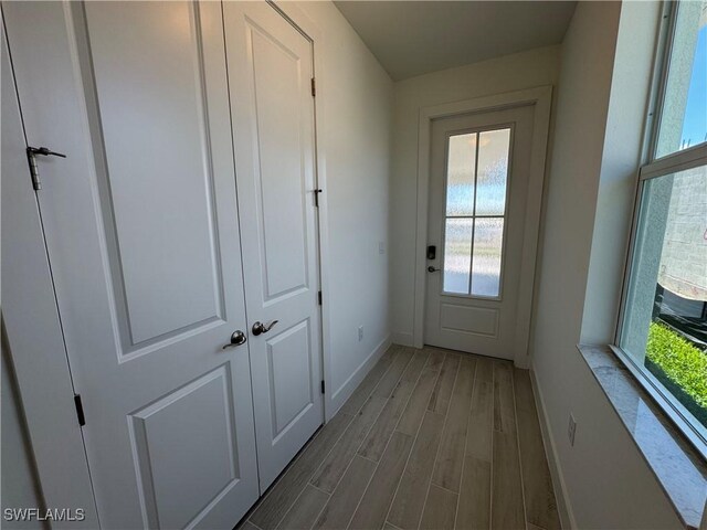 doorway to outside with plenty of natural light, wood finished floors, and baseboards