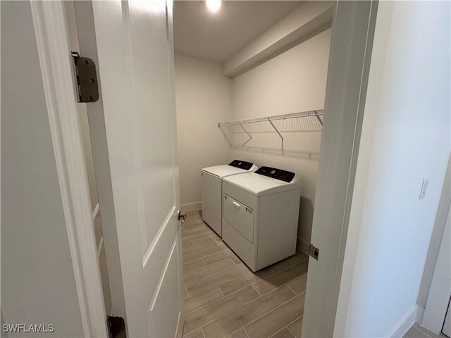 laundry area with laundry area, independent washer and dryer, baseboards, and wood finish floors