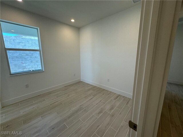 empty room featuring recessed lighting, wood finished floors, and baseboards