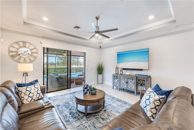 living room featuring a raised ceiling, ceiling fan, and ornamental molding