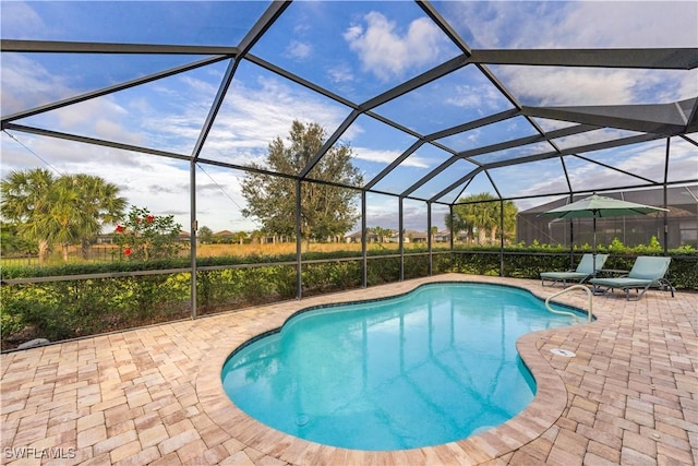 view of swimming pool featuring a patio and glass enclosure