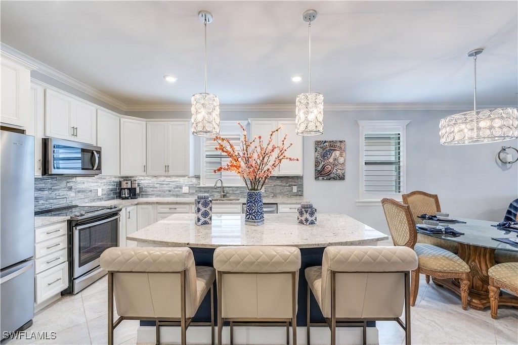 kitchen with light stone countertops, decorative light fixtures, stainless steel appliances, and a kitchen island