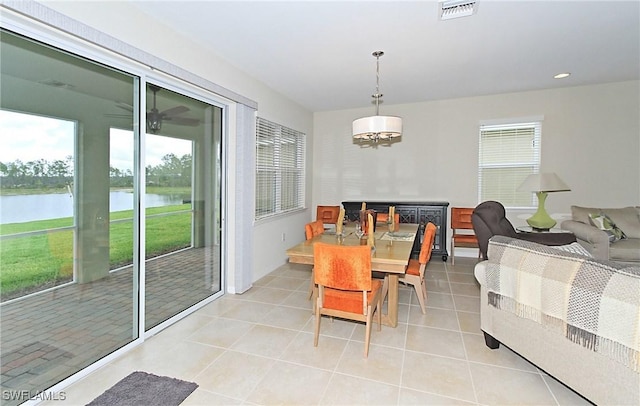 dining area with a notable chandelier, a water view, light tile patterned floors, and a wealth of natural light