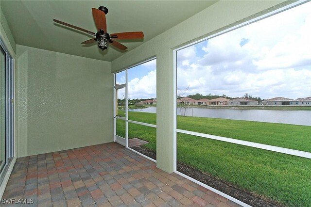 unfurnished sunroom with ceiling fan and a water view