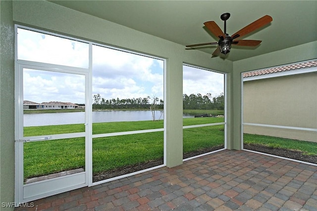 unfurnished sunroom with ceiling fan and a water view