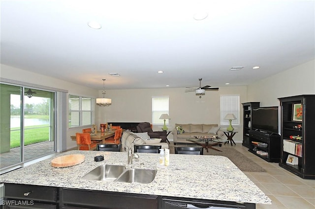 kitchen featuring a kitchen island with sink, sink, hanging light fixtures, and plenty of natural light