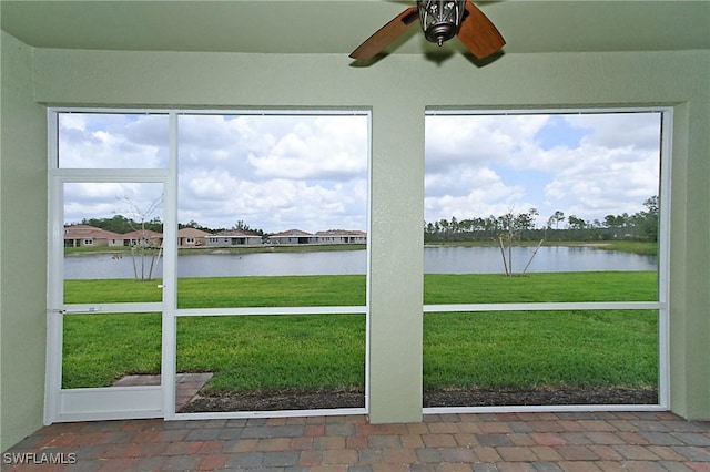 unfurnished sunroom featuring a water view and a ceiling fan