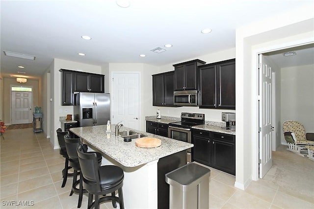 kitchen featuring appliances with stainless steel finishes, light tile patterned floors, a kitchen island with sink, and sink