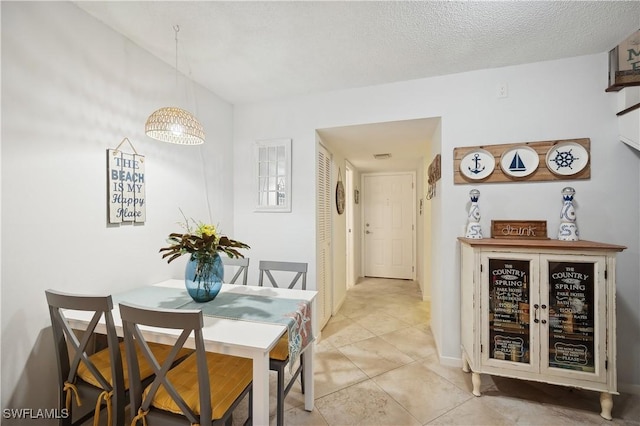 tiled dining room featuring a textured ceiling