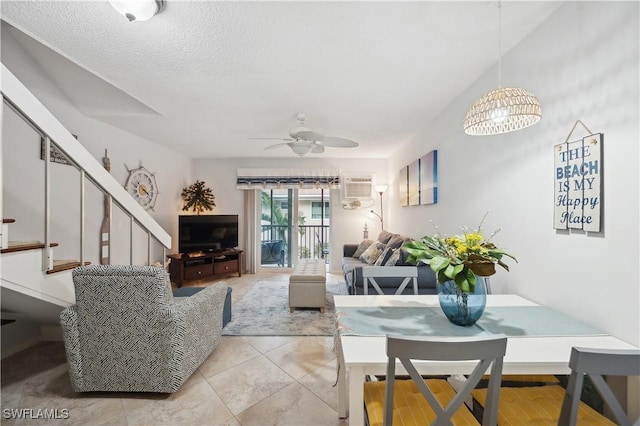 tiled living room featuring a wall mounted air conditioner, a textured ceiling, and ceiling fan