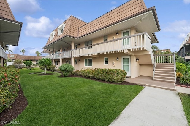 back of property featuring a balcony and a yard