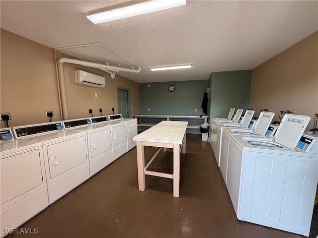 laundry room featuring washing machine and clothes dryer, a textured ceiling, and a wall mounted air conditioner