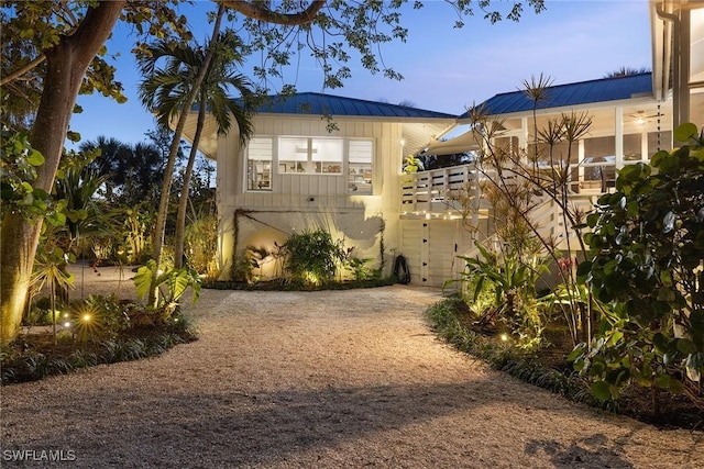 back of house featuring dirt driveway and metal roof