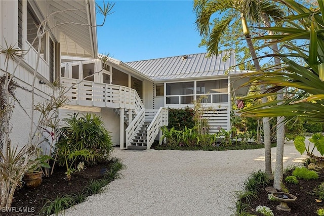 exterior space with metal roof, stairway, and a sunroom