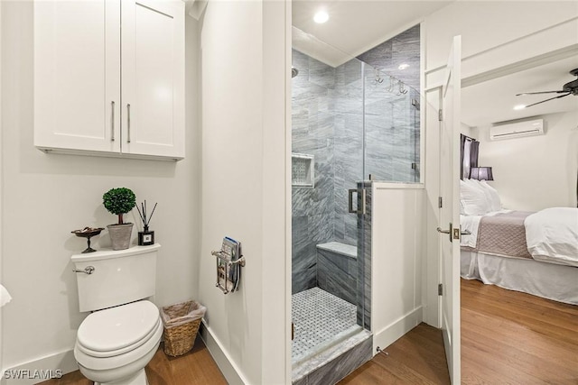 ensuite bathroom with a wall unit AC, toilet, wood finished floors, a shower stall, and ensuite bath