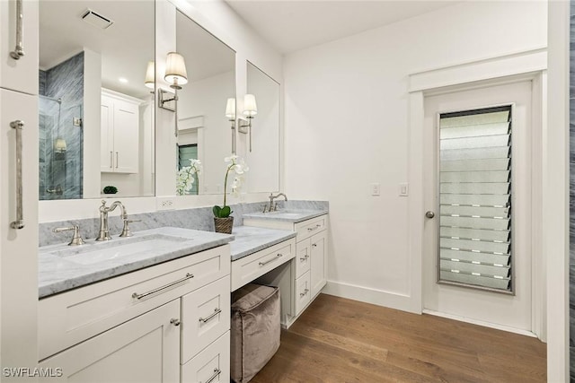 bathroom featuring a shower, visible vents, vanity, wood finished floors, and baseboards