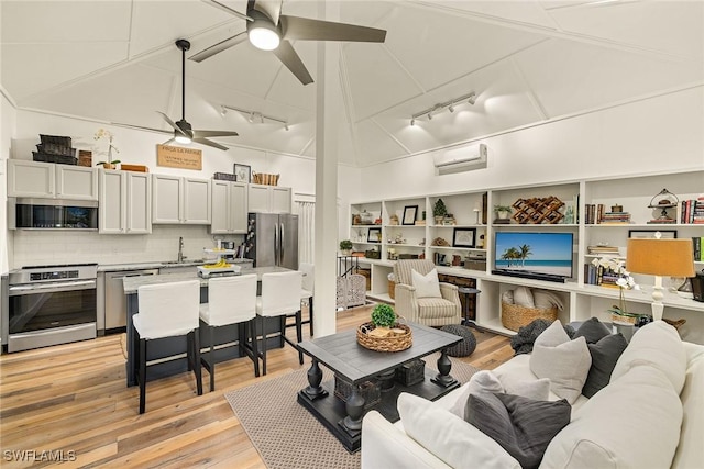 living room with ceiling fan, an AC wall unit, and light wood-style flooring