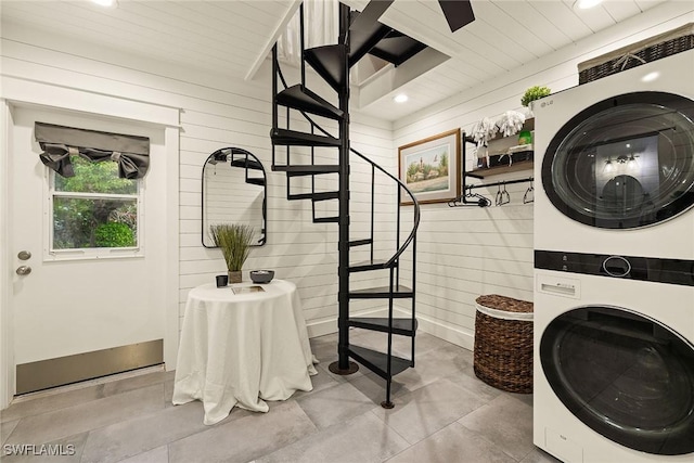 laundry area with laundry area, wood walls, and stacked washer / drying machine