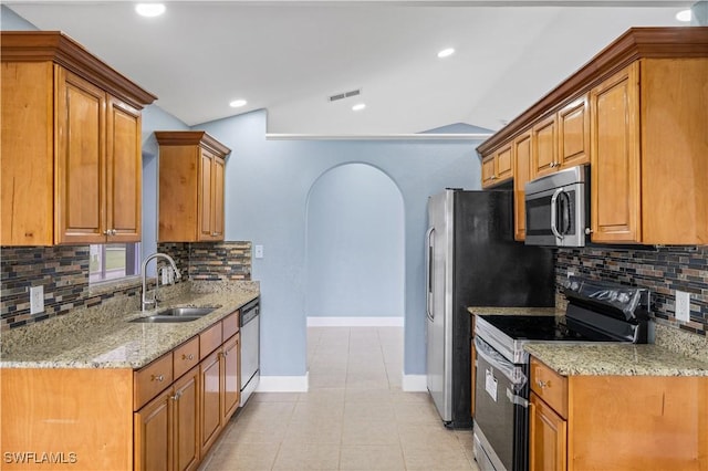 kitchen featuring backsplash, light stone counters, sink, and stainless steel appliances