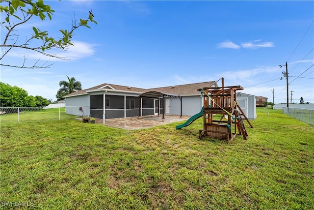 rear view of property featuring a lawn, a patio area, and a playground