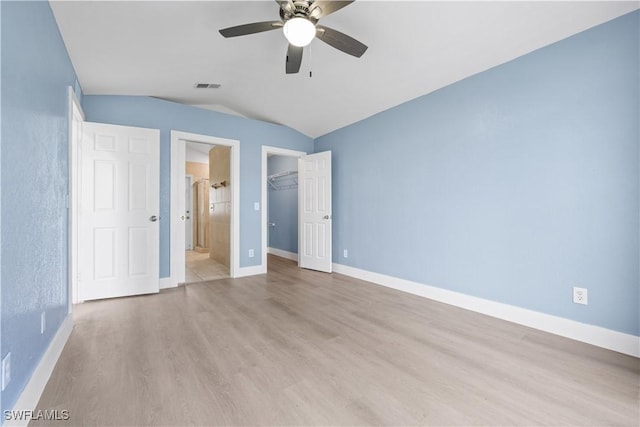 unfurnished bedroom featuring vaulted ceiling, light hardwood / wood-style flooring, ceiling fan, connected bathroom, and a closet