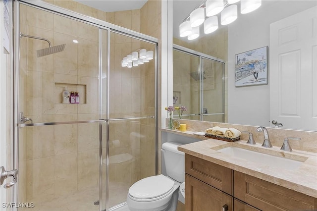 bathroom with vanity, a shower with door, and toilet