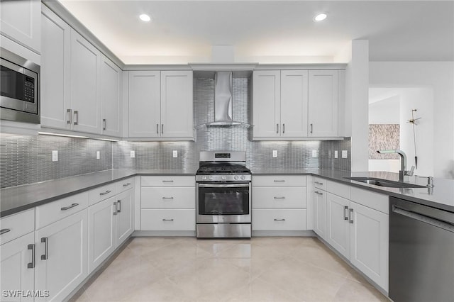 kitchen featuring appliances with stainless steel finishes, sink, white cabinets, decorative backsplash, and wall chimney exhaust hood