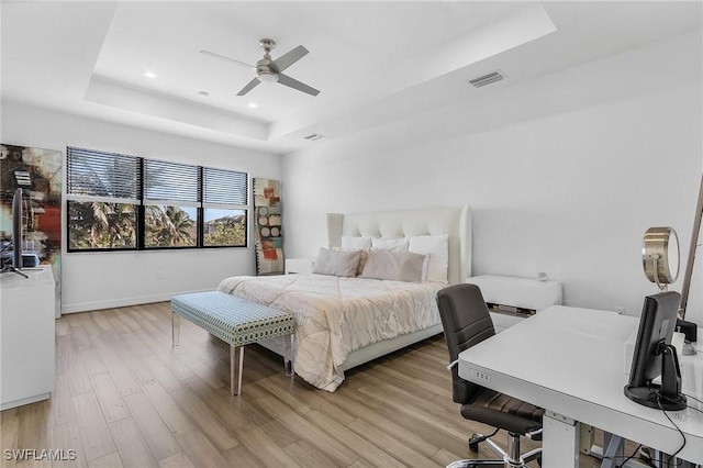 bedroom featuring a tray ceiling, light hardwood / wood-style floors, and ceiling fan