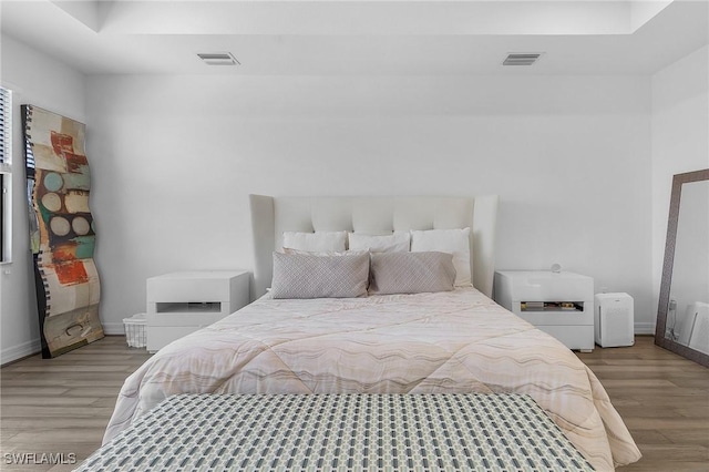 bedroom with a raised ceiling and light hardwood / wood-style flooring