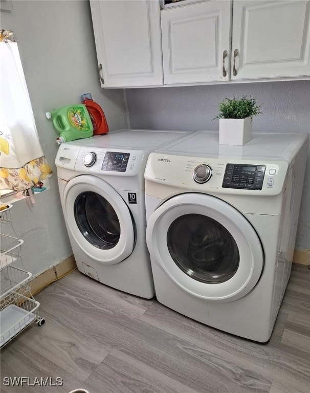 laundry room with cabinets, independent washer and dryer, and light hardwood / wood-style flooring