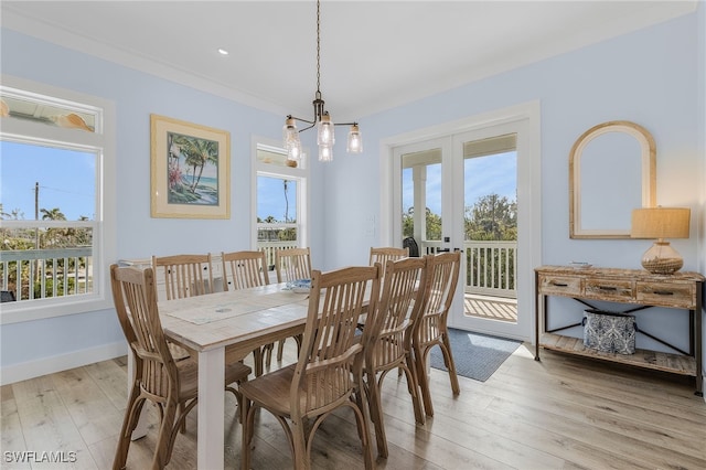 dining room with a notable chandelier, light hardwood / wood-style floors, ornamental molding, and french doors