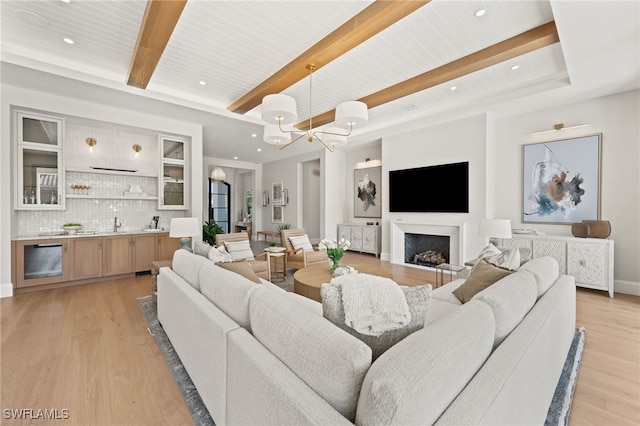 living room featuring bar, a notable chandelier, light hardwood / wood-style floors, wooden ceiling, and beam ceiling