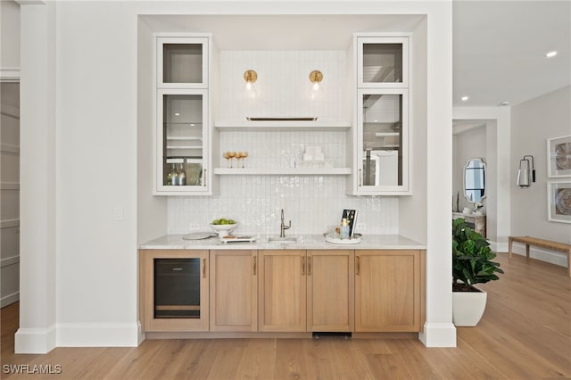 bar with backsplash, light hardwood / wood-style flooring, and light brown cabinets